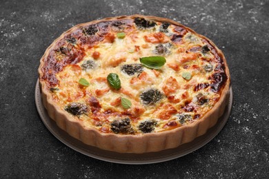 Photo of Delicious homemade quiche with salmon and broccoli on black table