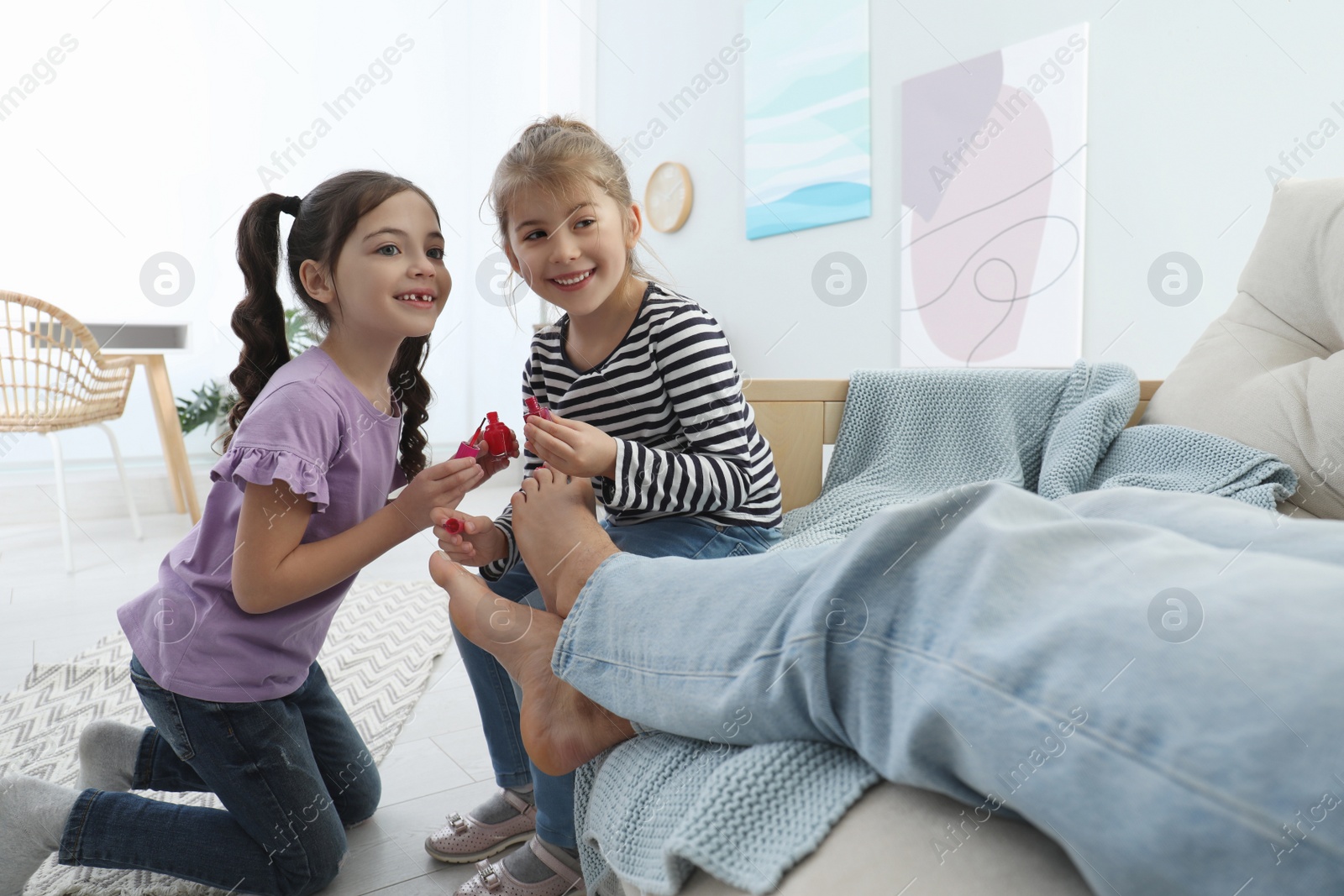 Photo of Cute little children applying polish on father's nails while he sleeping at home, closeup