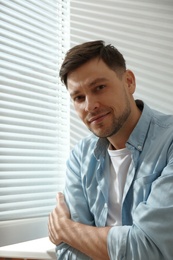 Handsome man near window with Venetian blinds