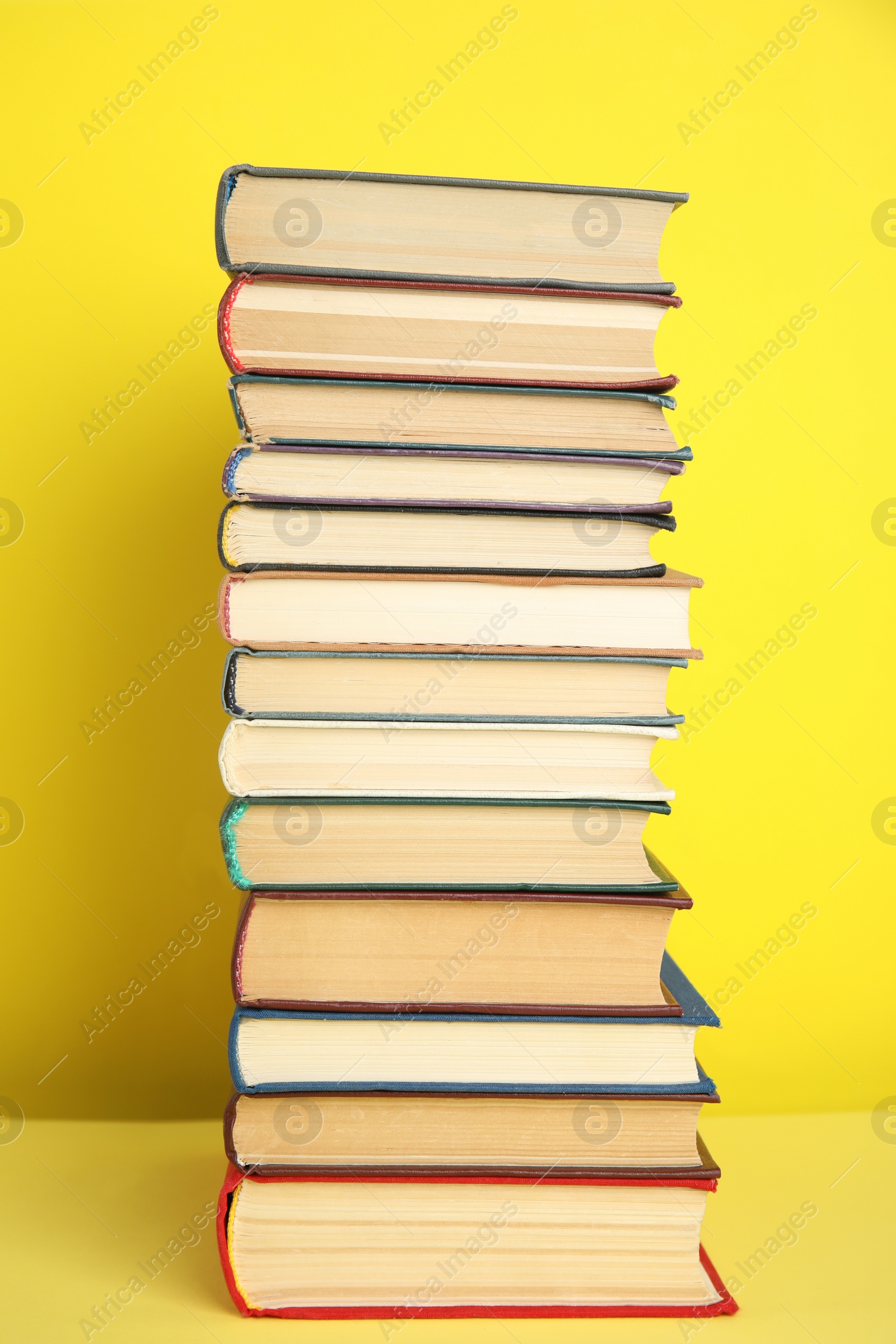 Photo of Stack of different hardcover books on yellow background