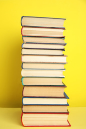 Photo of Stack of different hardcover books on yellow background