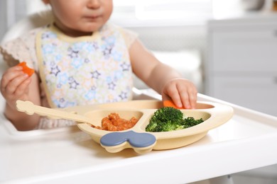 Little baby eating food in high chair, closeup