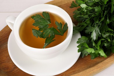 Photo of Aromatic herbal tea and fresh parsley on table, closeup