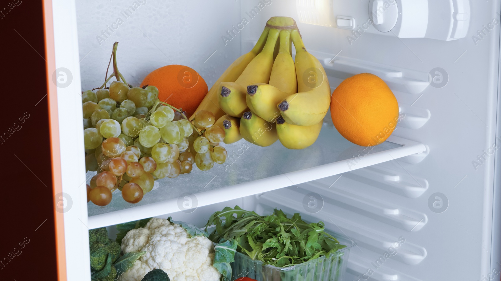 Photo of Open refrigerator with many different fresh vegetables and fruits