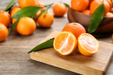 Fresh ripe tangerines with green leaves on wooden table