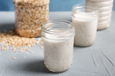 Jars with oat milk and flakes on table