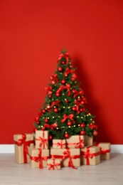 Photo of Blurred view of decorated Christmas tree and gift boxes near red wall