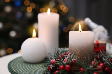Photo of Beautiful burning candles and Christmas decor on white table indoors