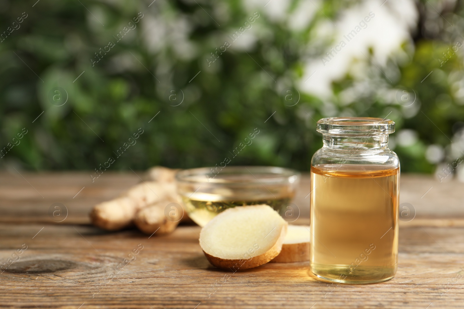 Photo of Ginger essential oil in bottle on wooden table. Space for text