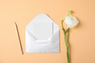 Photo of Flat lay composition with beautiful ranunculus flower and card in envelope on color background. Space for text