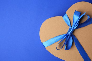 Photo of Beautiful heart shaped gift box with bow on blue background, top view. Space for text