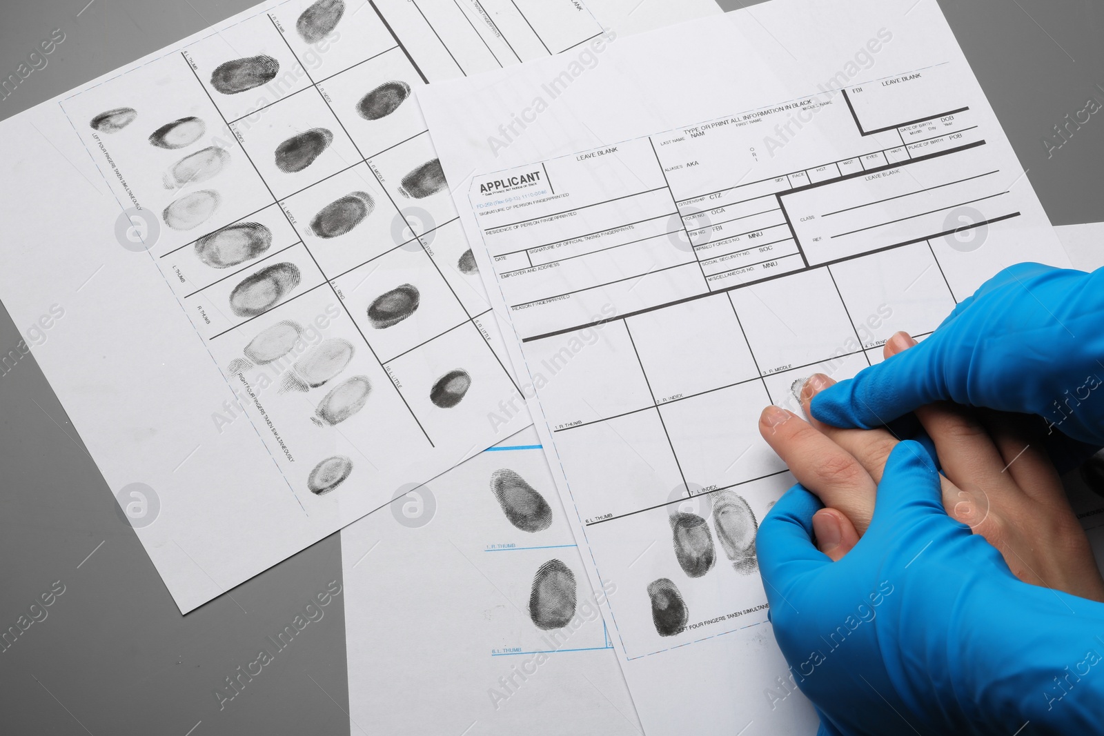 Photo of Investigator taking fingerprints of suspect at table, top view. Criminal expertise