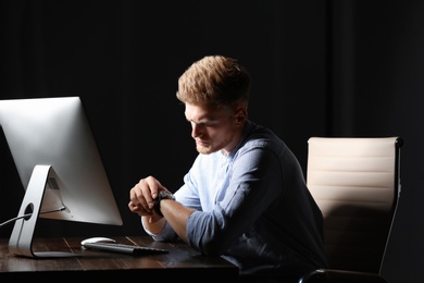 Photo of Tired young man working in office alone at night