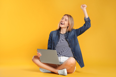 Photo of Emotional young woman with laptop on yellow background