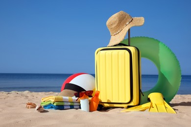 Photo of Suitcase and stylish beach accessories on seaside