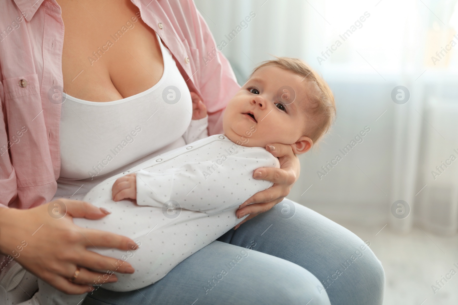 Photo of Young woman with her cute baby at home, closeup