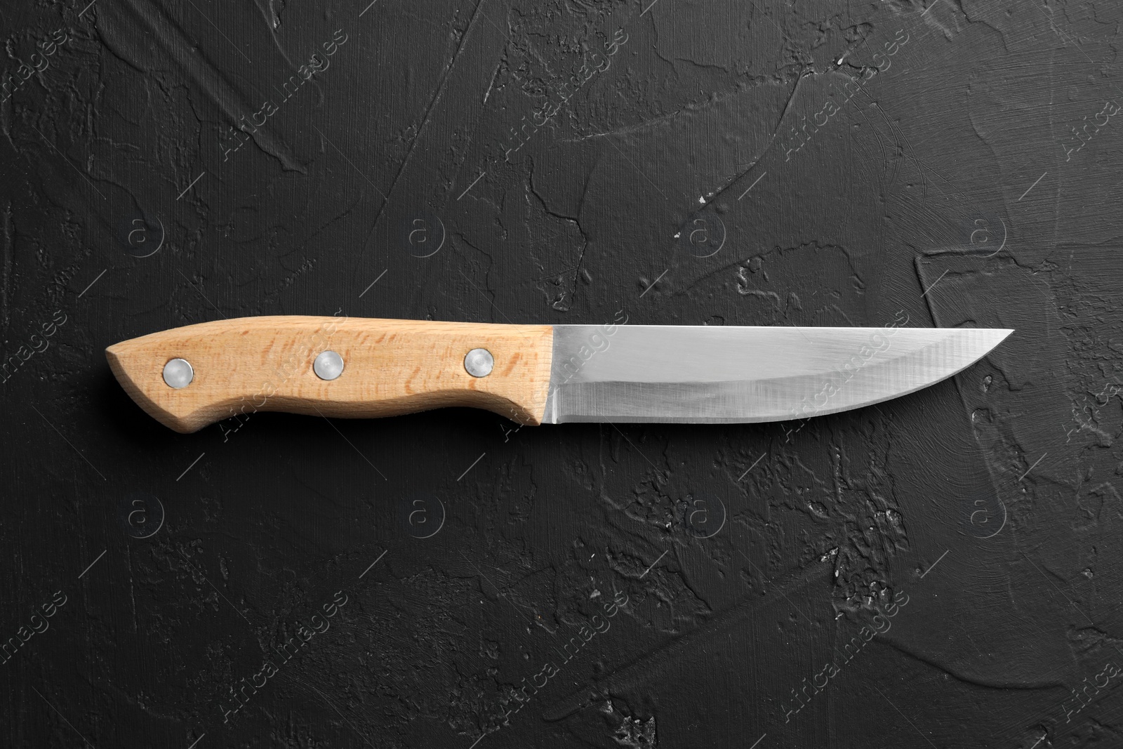 Photo of One sharp knife on dark textured table, top view