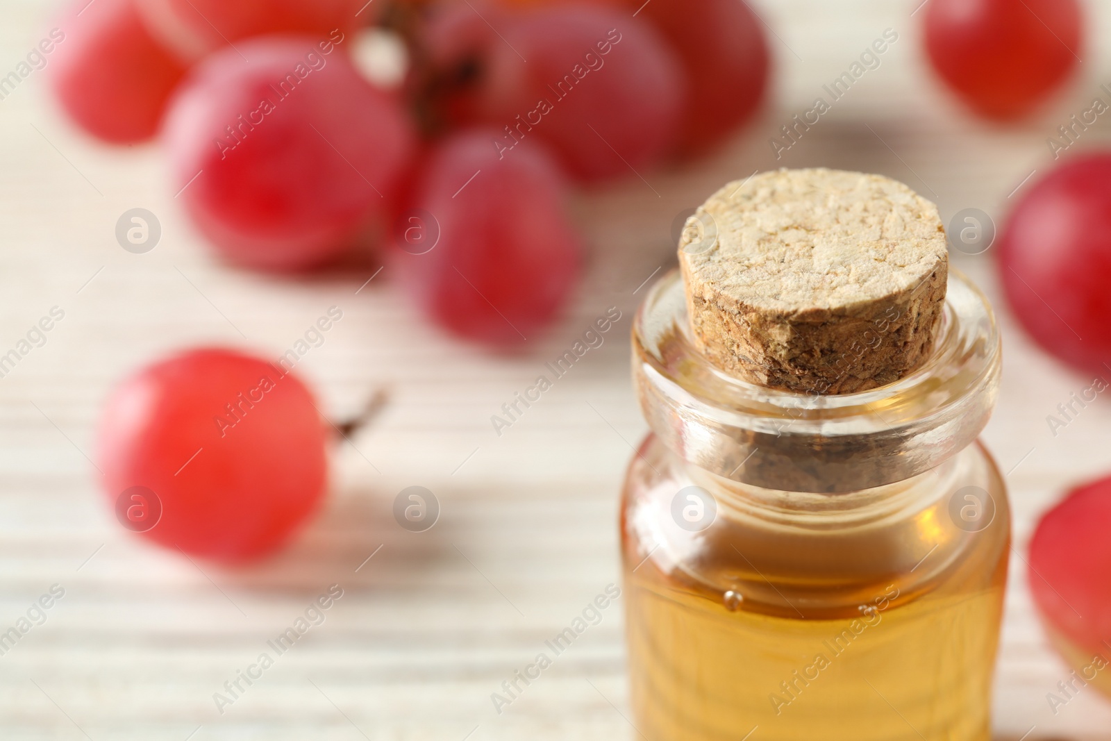 Photo of Bottle of natural grape seed oil on white table, closeup with space for text. Organic cosmetic