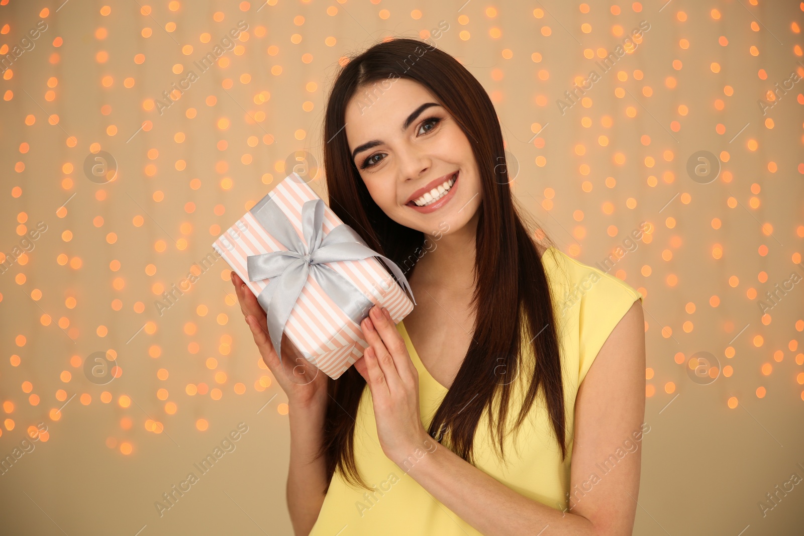 Photo of Portrait of beautiful smiling girl with gift box on blurred background. International Women's Day