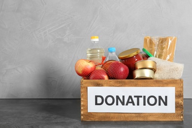 Photo of Donation box with food on table against light background. Space for text