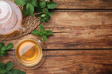 Photo of Cup of hot aromatic mint tea on wooden table, flat lay. Space for text