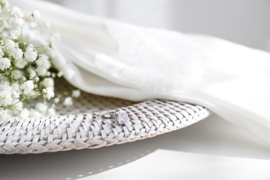 Beautiful engagement ring, wedding dress and flowers on table indoors, closeup