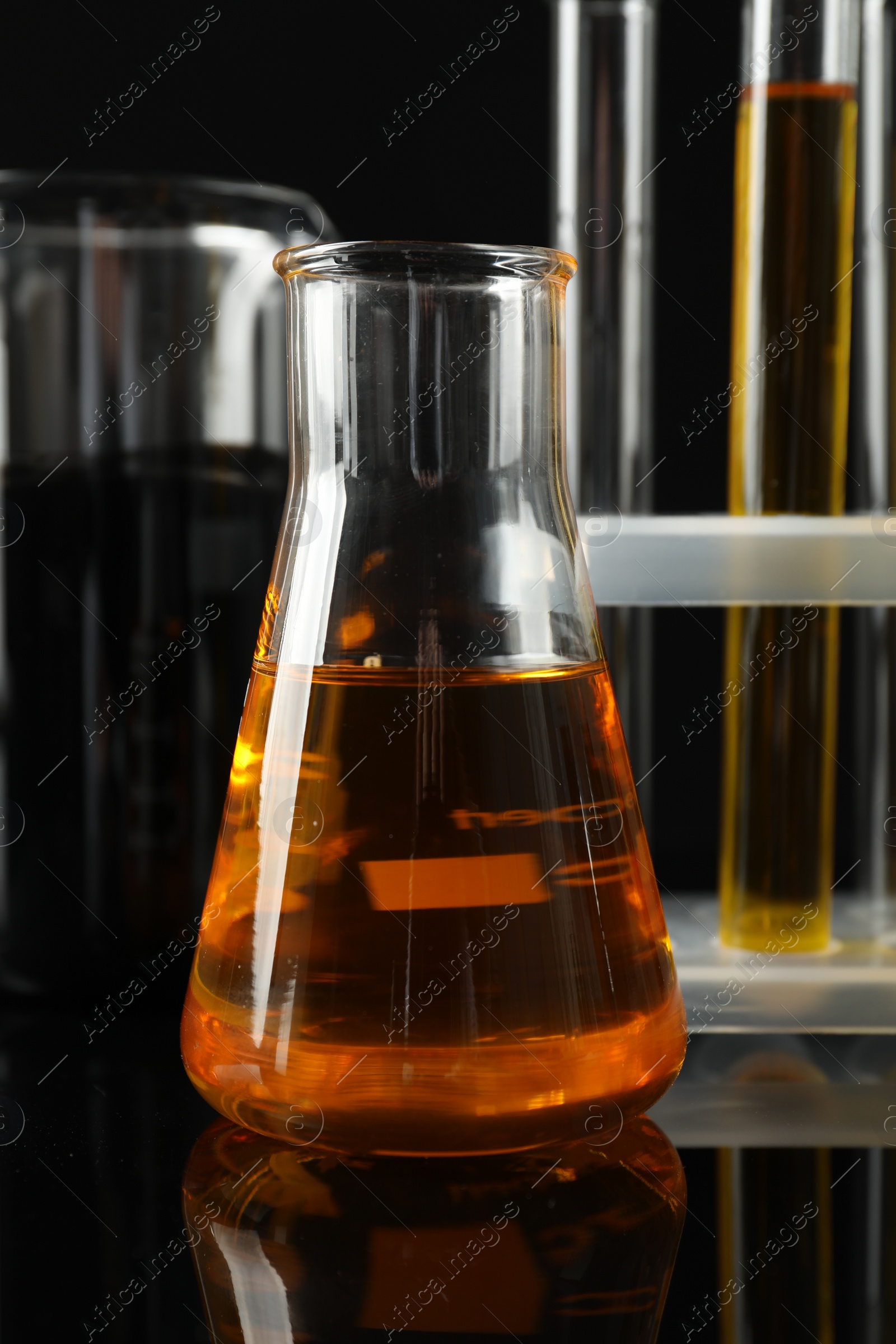 Photo of Laboratory glassware with different types of oil on black background, closeup