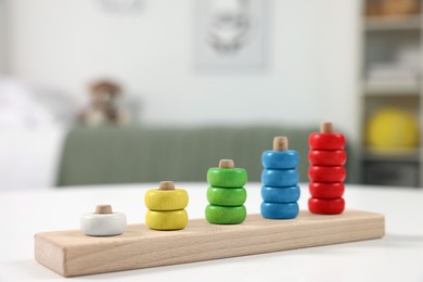 Photo of Motor skills development. Stacking and counting game wooden pieces on white table indoors, closeup