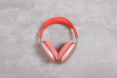 Photo of Stylish pink headphones on light grey table, top view