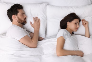 Photo of Lovely couple sleeping together in bed at home, top view