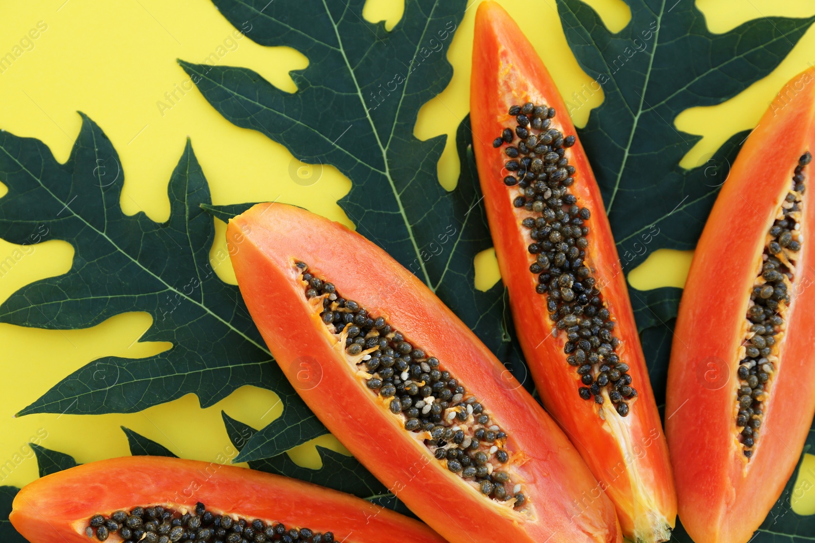 Photo of Fresh ripe papaya slices and leaf on yellow background, flat lay