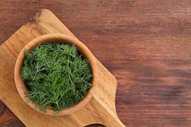 Photo of Bowl of fresh dill on wooden table, top view. Space for text