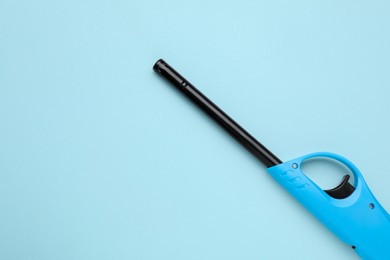 Photo of One gas lighter on light blue background, top view. Space for text