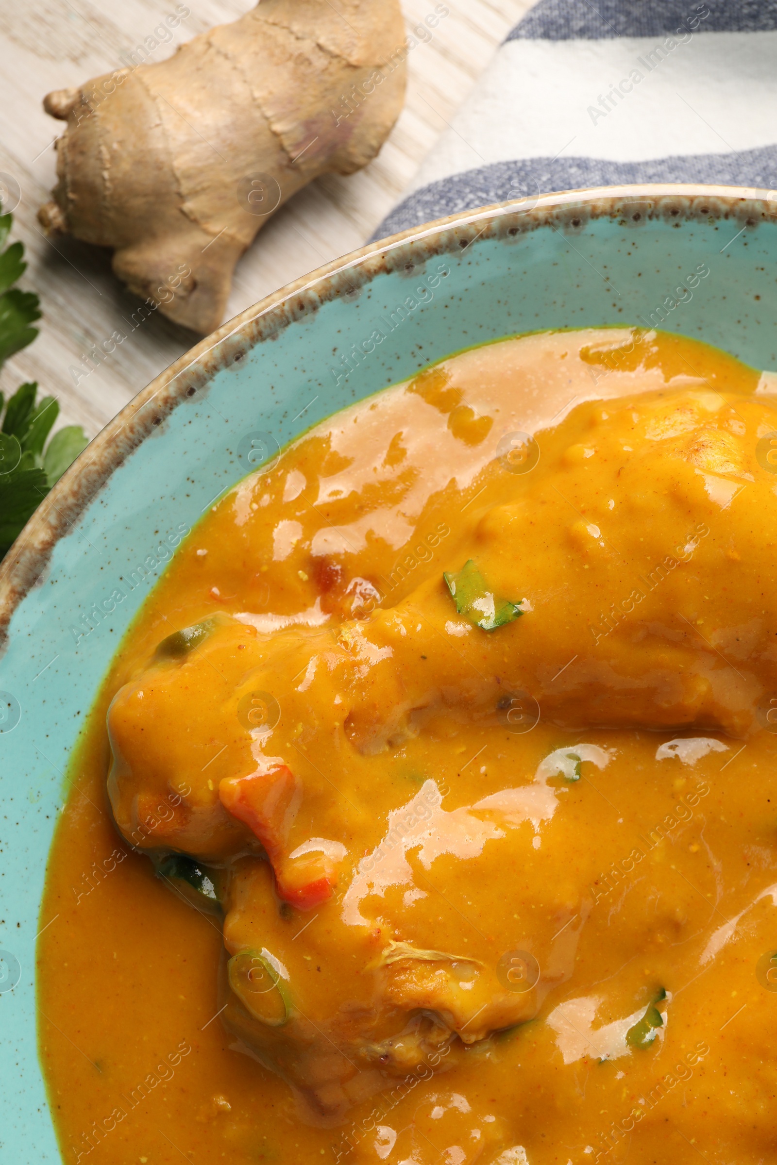 Photo of Tasty chicken curry and ginger on wooden table, flat lay