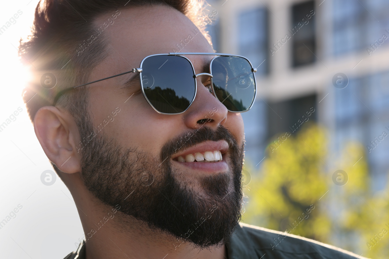 Photo of Handsome smiling man in sunglasses outdoors, closeup. Space for text