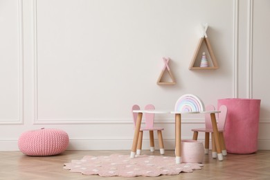 Photo of Cute child room interior with furniture, toys and wigwam shaped shelves on white wall