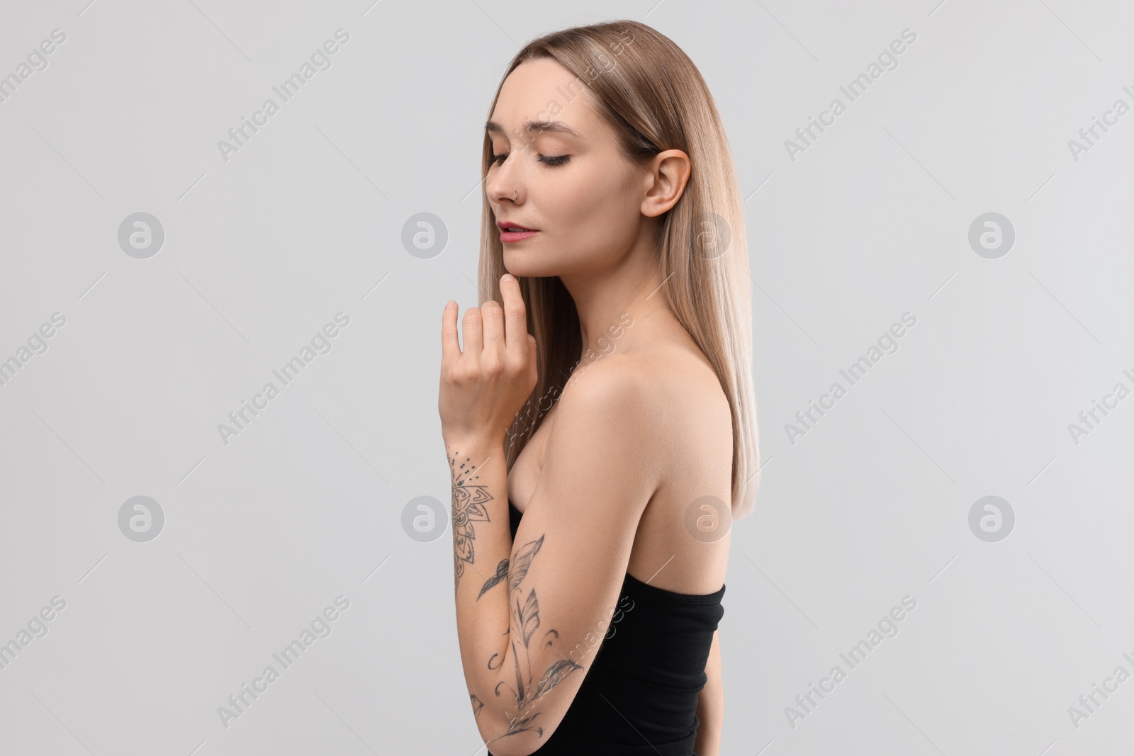 Photo of Portrait of beautiful tattooed woman on light background