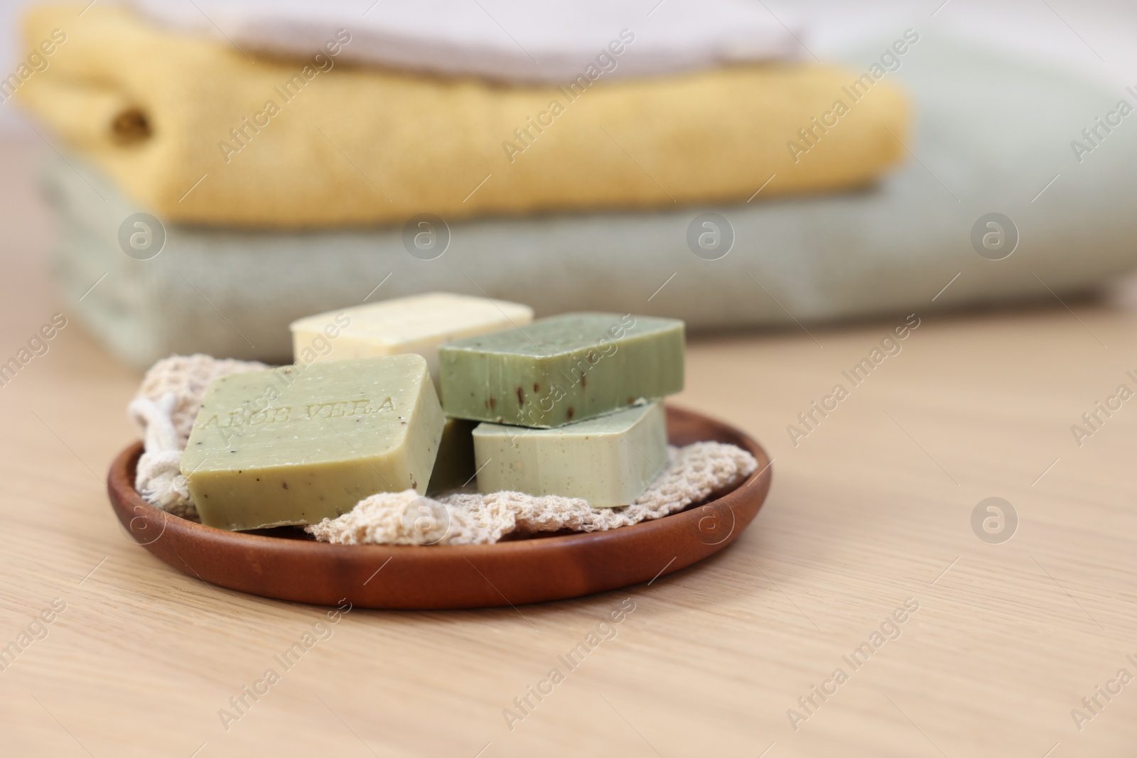 Photo of Tray with soap bars on light wooden table, space for text. Spa therapy