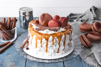 Delicious homemade cake with caramel sauce and cookies on table