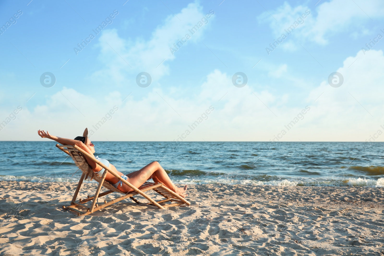 Photo of Young woman relaxing in deck chair on beach