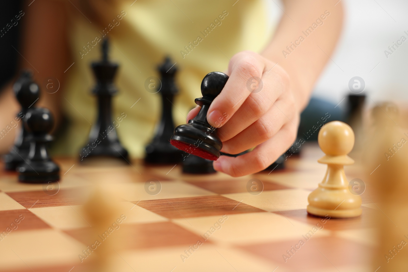 Photo of Little child playing chess, closeup of hand