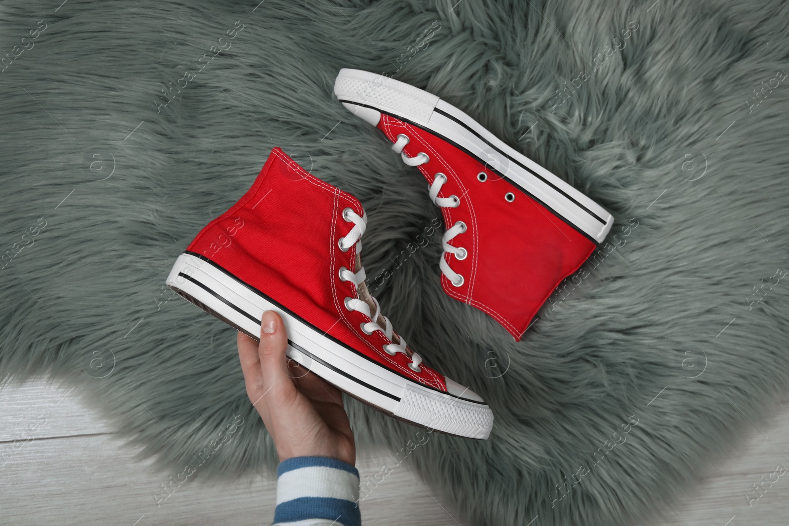 Photo of Woman with new stylish red sneakers on fluffy rug, top view