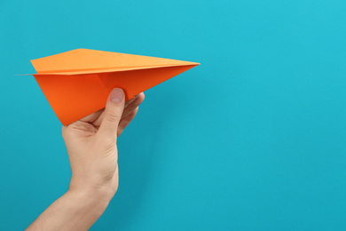 Woman holding paper plane on light blue background, closeup. Space for text