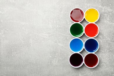 Photo of Bowls with many different food coloring on light grey table, flat lay. Space for text