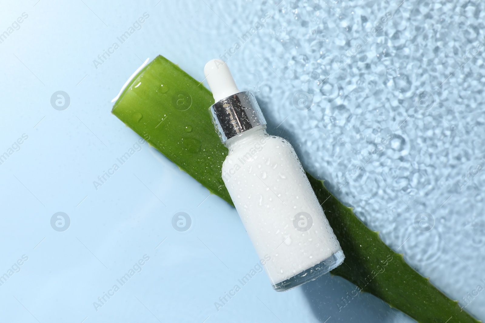 Photo of Bottle of cosmetic product and aloe leaf in water on light blue background, flat lay