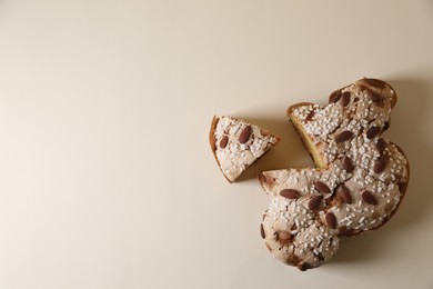 Photo of Delicious cut Italian Easter dove cake (traditional Colomba di Pasqua) on beige table, flat lay. Space for text