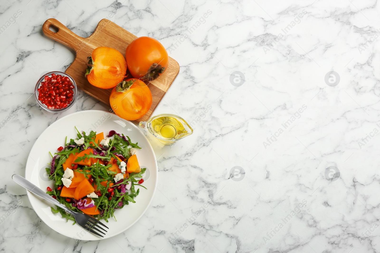 Photo of Delicious persimmon salad served on white marble table, flat lay. Space for text