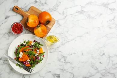 Delicious persimmon salad served on white marble table, flat lay. Space for text