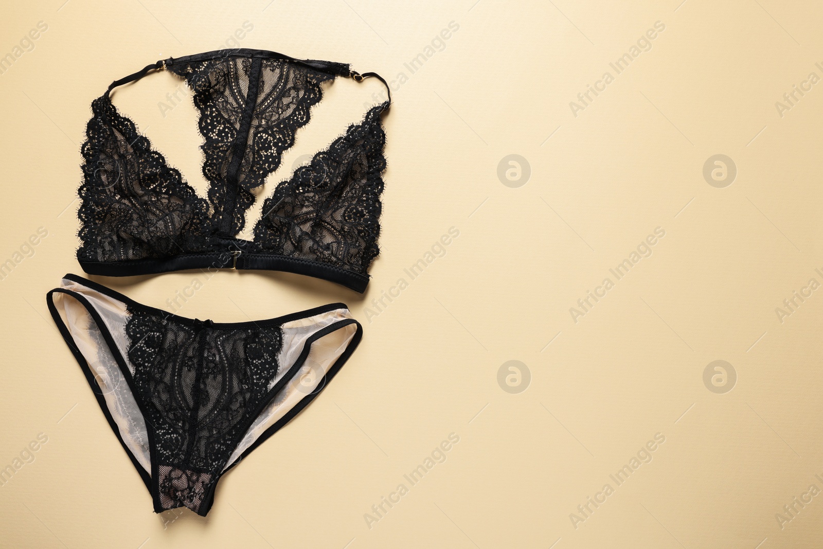 Photo of Elegant black women's underwear on beige background, flat lay. Space for text