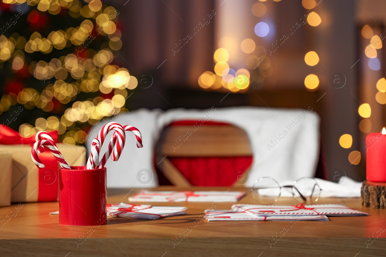 Photo of Santa's Claus workplace. Letters and candy canes on table in room with Christmas decor